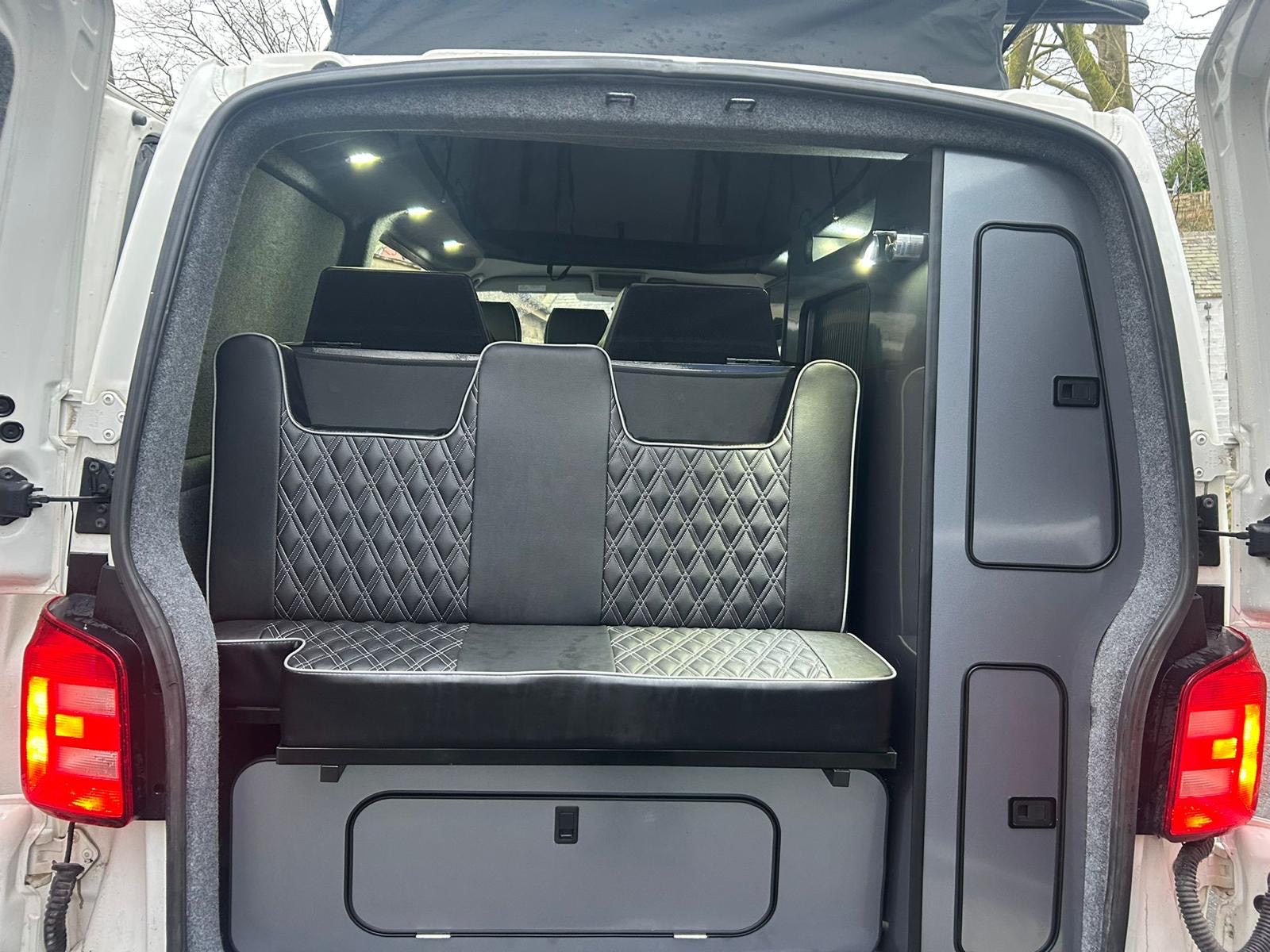 Volkswagen T6 camper van for hire with NW Car Hire, showing rear interior seating and storage units.